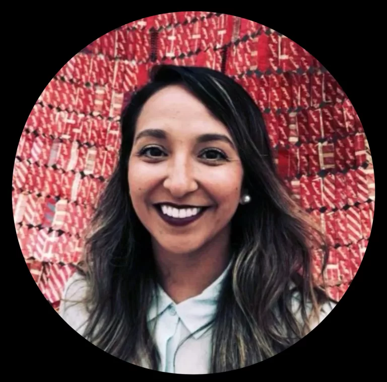 A person with privileged brown skin, brown eyes, and long brown hair, who identifies as chicana and is smiling at the camera.